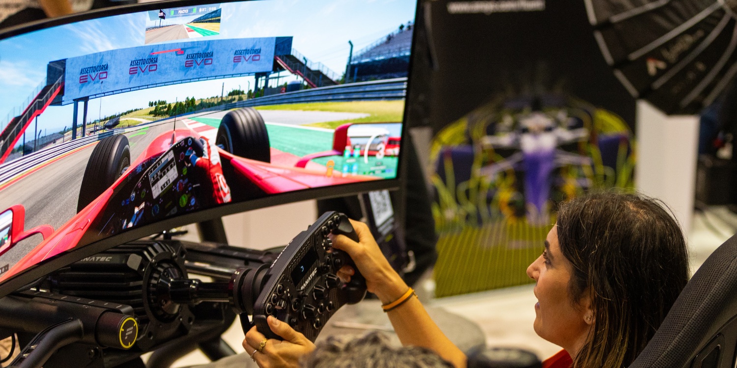 An attendee trying a driving simulator on the AI Infra Summit 2026 exhibition floor